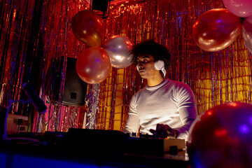 African american dj in headphones playing music at a nightclub in low light