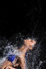 Obraz na płótnie Canvas Tanned skin Asian woman in bikini poses in aqua studio. Splash Drops of water spread to body. Fun emotion female girl on water attack fluttering and stop motion freeze shot, black background isolated