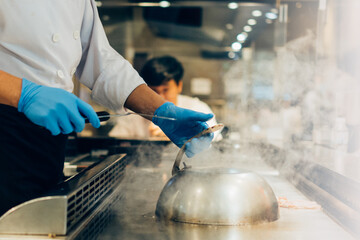 Hand of man take cooking of meat with vegetable grill, Chef cooking wagyu beef in Japanese teppanyaki restaurant