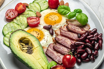 Keto breakfast with avocado, fried eggs, bacon, and beans. paleo keto breakfast diet lunch. Healthy nutritious paleo keto breakfast concept. Food recipe background. Close up