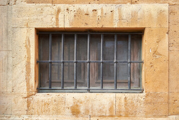 Fototapeta na wymiar window with grill and metal mesh on stone wall