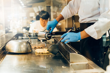 Hand of man take cooking of meat with vegetable grill, Chef cooking wagyu beef in Japanese teppanyaki restaurant