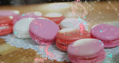 Blue QR code with a red floating web of connections over pink macaronies lying on a table
