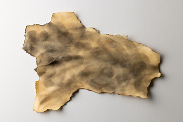 Burned and stained piece of paper with copy space on white background