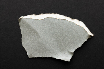 Ripped up piece of gray paper with copy space on black background