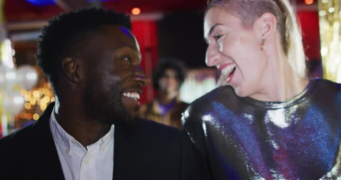 Video of diverse happy couple walking into nightclub talking and laughing