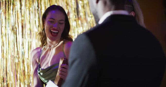 Video of diverse doorman greeting happy female friends walking into nightclub arm in arm laughing