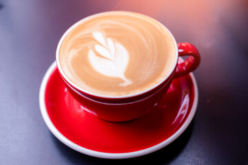 Coffee in a cup placed on a wooden table, close view