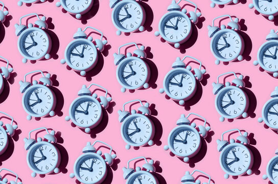 Seamless pattern of old white alarm clocks on pink background
