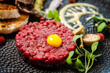 Beef tartare from Black Angus. Onion, quail egg, tomato sauce, mustard mayonnaise. Delicious healthy Italian traditional food closeup served for lunch in modern gourmet cuisine restaurant
