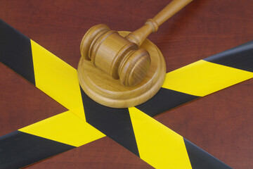 Wooden gavel and yellow and black barrier tapes close up. 