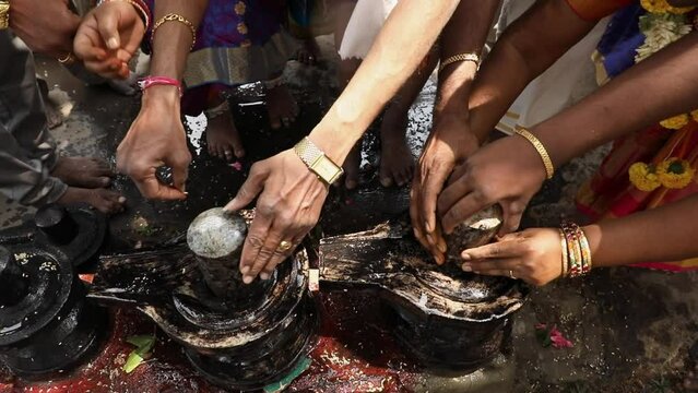 Family hands fixing or establishing shivalinga at temple