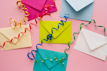 Top view of colorful serpentine on envelopes on pink background.