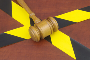 Wooden judge gavel on yellow and black barrier tapes. Crimes, law and investigation concept.