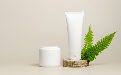 Cosmetic bottle containers mockup. Face cream on wooden podium with fern leaves. Natural organic...