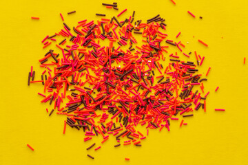 Naklejka premium Top view of colorful sprinkles on yellow background.
