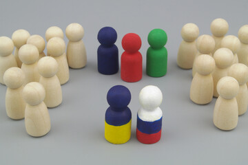 Obraz premium Wooden people figures are divided into two parts, and leaders is painted in colors of Ukrainian and Russian flags with international mediators. Peace between Russia and Ukraine concept. 