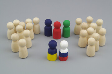 Wooden people figures are divided into two parts, and leaders is painted in colors of Ukrainian and Russian flags with international mediators. Peace between Russia and Ukraine concept. 