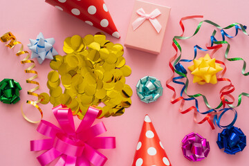 Top view of confetti near serpentine and gift box on pink background.