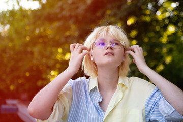 Closeup portrait of stylish teenage girl outdoor in wireless headphones.Sunlight on background.