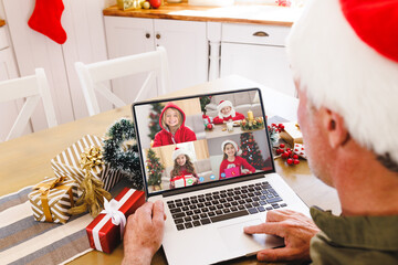 Senior caucasian man having christmas video call with diverse children