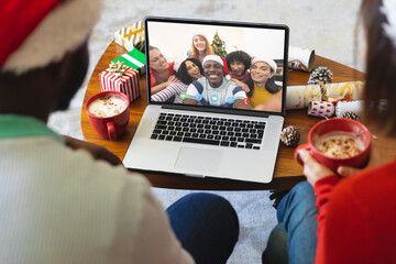Diverse couple having christmas video call with diverse people