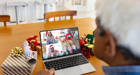 Biracial man with santa hat having video call with happy diverse friends - Powered by Adobe
