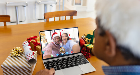 Biracial man with santa hat having video call with happy diverse couple - Powered by Adobe