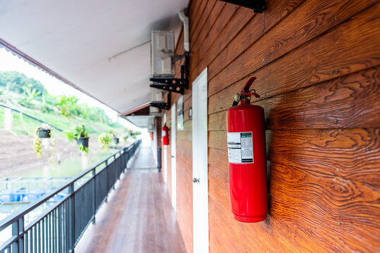 Fire Extinguisher Hanging At Wooden Wall.