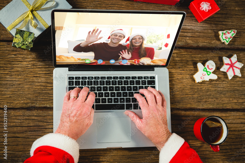 Canvas Prints Santa claus with christmas presents having video call with happy caucasian couple