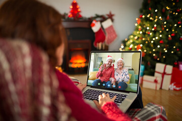 Caucasian woman with christmas decorations having video call with happy senior caucasian couple