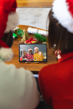 Diverse couple with christmas decorations having video call with happy diverse couple