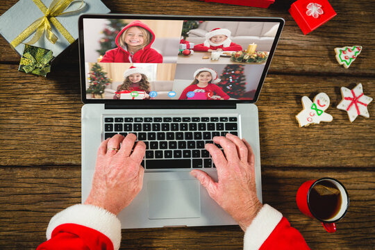 Santa claus with christmas presents having video call with happy caucasian children