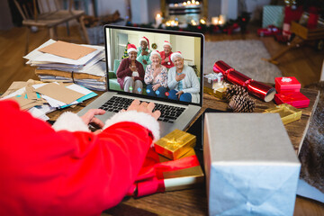 Obraz na płótnie Canvas Santa claus having video call with happy senior diverse friends