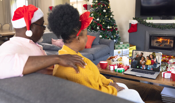 African american couple with santa hats having video call with happy african american family