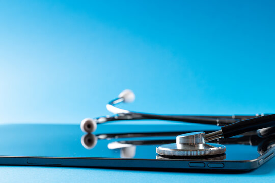 Composition of stethoscope with tablet on blue background, with copy space