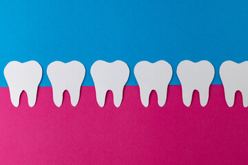 Composition of row of white teeth in pink gum on blue background, with copy space