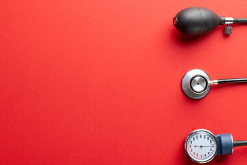 Composition of sphygmomanometer and stethoscope on red background with copy space