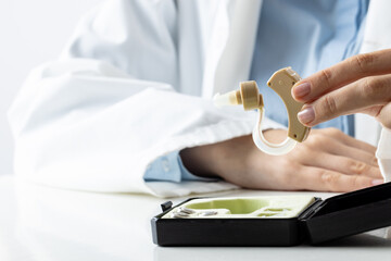 Obraz premium Midsection of caucasian female doctor holding hearing aid