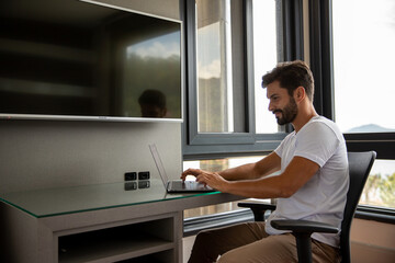 person working on computer, young bearded man sitting in front of his computer working from home, home office, handsome young man working on his computer, answering email