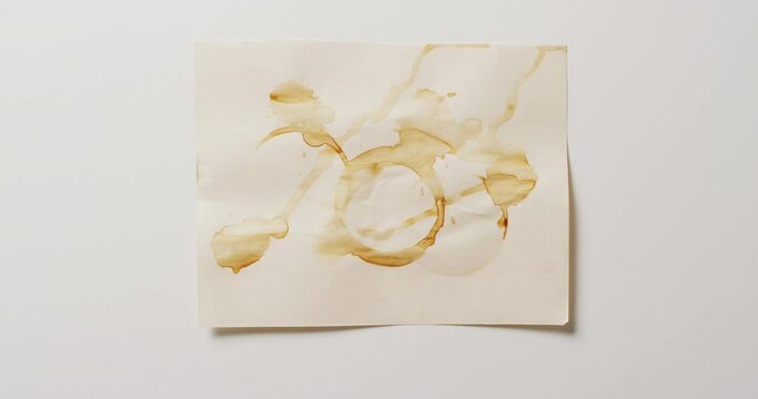 Video of close up of piece of paper with round coffee mug stains on white background