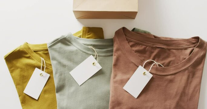 Video of close up of folded t shirts with tags on white background