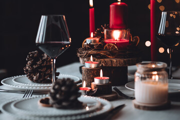 Rustic table decor for Christmas or New Year family dinner. Centrepiece with red candle, dry orange, cone, cinnamon, anise. Zero waste eco-friendly home. Cozy atmosphere, dark background. Close up