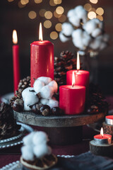 Rustic table decor for Christmas or New Year family dinner. Centrepiece with red candle, dry orange, cone, cinnamon, anise. Zero waste eco-friendly home. Cozy atmosphere, dark background. Close up