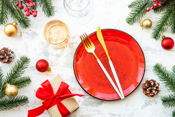 Christmas table setting with craft plate, cutlery, gift box and christmas decorations on white wooden table. Top view image.