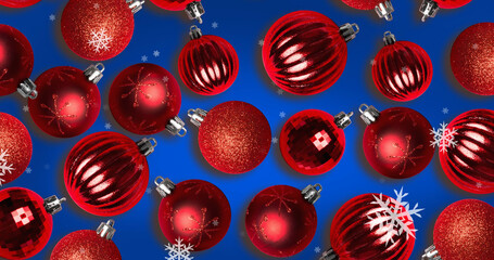 Image of snow falling over christmas bauble decorations on blue background