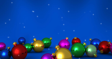 Image of snow falling over christmas bauble decorations on blue background