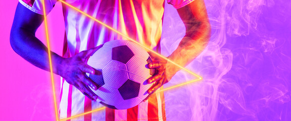 Midsection of biracial male player holding ball by illuminated triangle and smoke, copy space