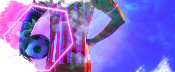 Midsection of biracial man with hand on hip holding ball by illuminated hexagon over smoke