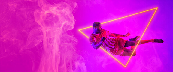 African american male soccer player jumping by illuminated triangle, copy space